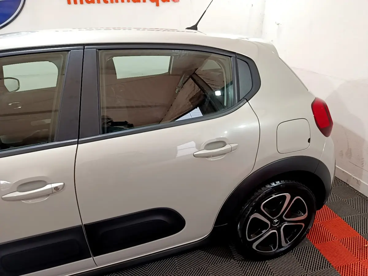 Vue latérale côté droit d'une Citroën C3 beige 2022 avec protections noires sur les portières et jantes stylisées.