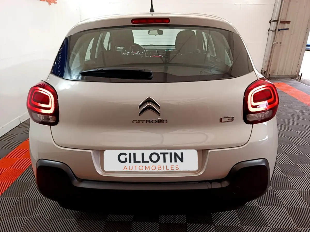 Vue arrière d'une Citroën C3 beige 2022 avec feux arrière LED et logo centré sur un fond intérieur.