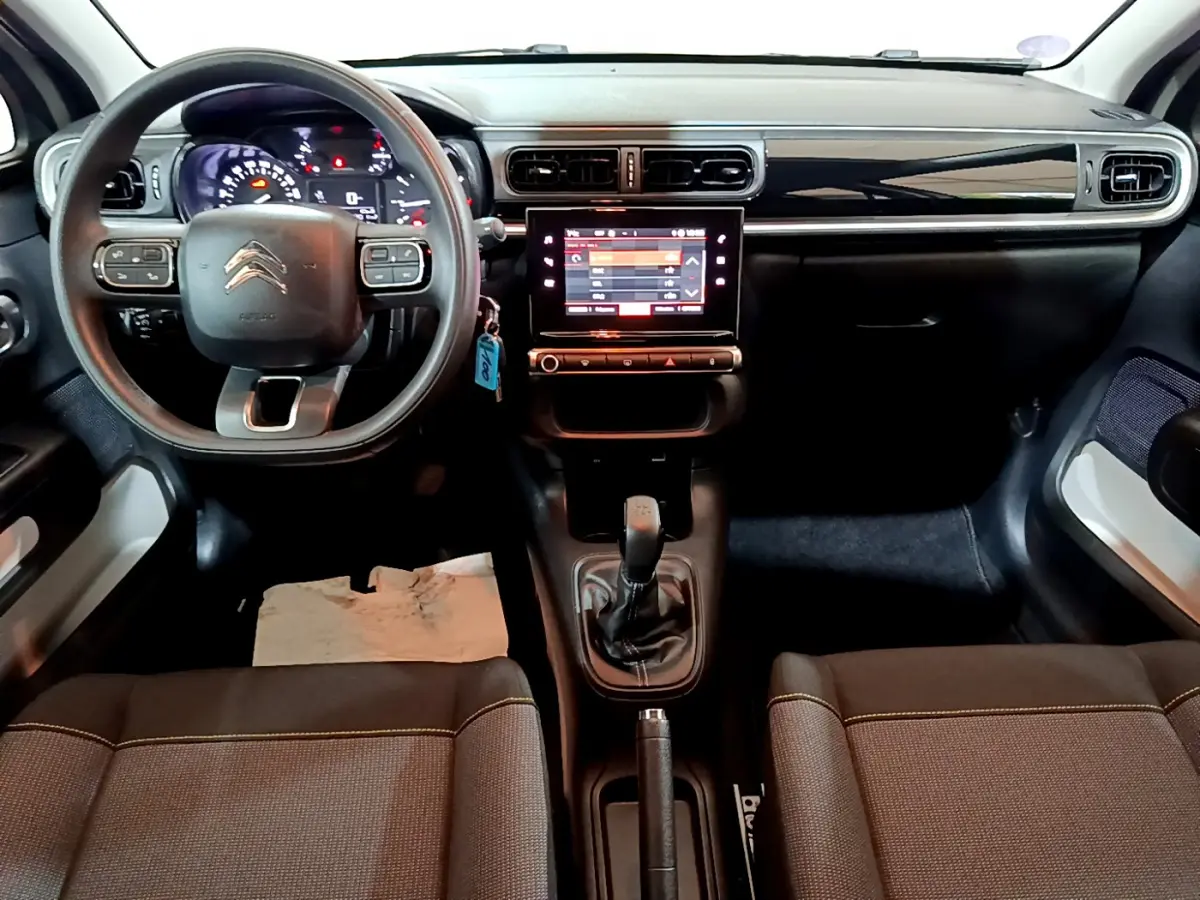 Vue intérieure avant de la Citroën C3 beige 2022, tableau de bord avec écran tactile central et volant multifonctions.