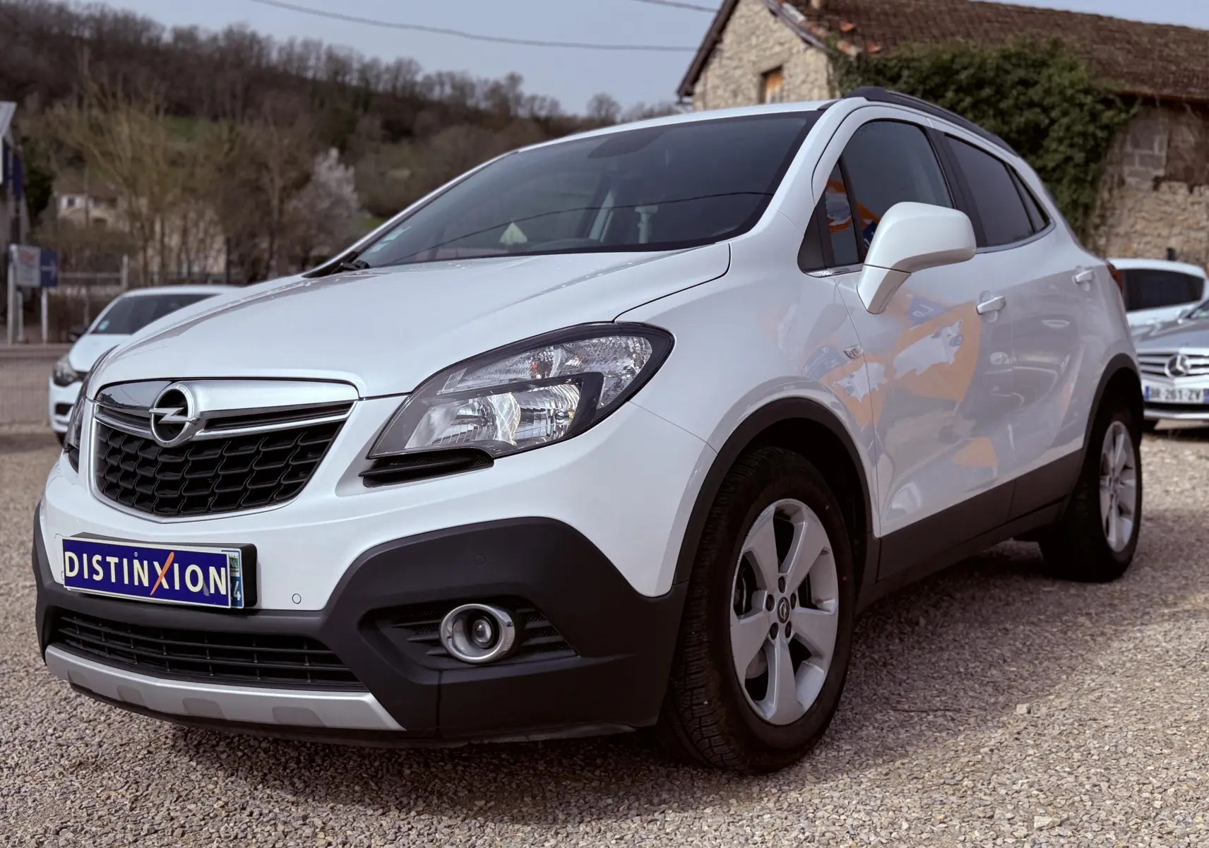Opel Mokka X blanc vue 3/4 avant droit, avec calandre noire et jantes alliage cinq branches.