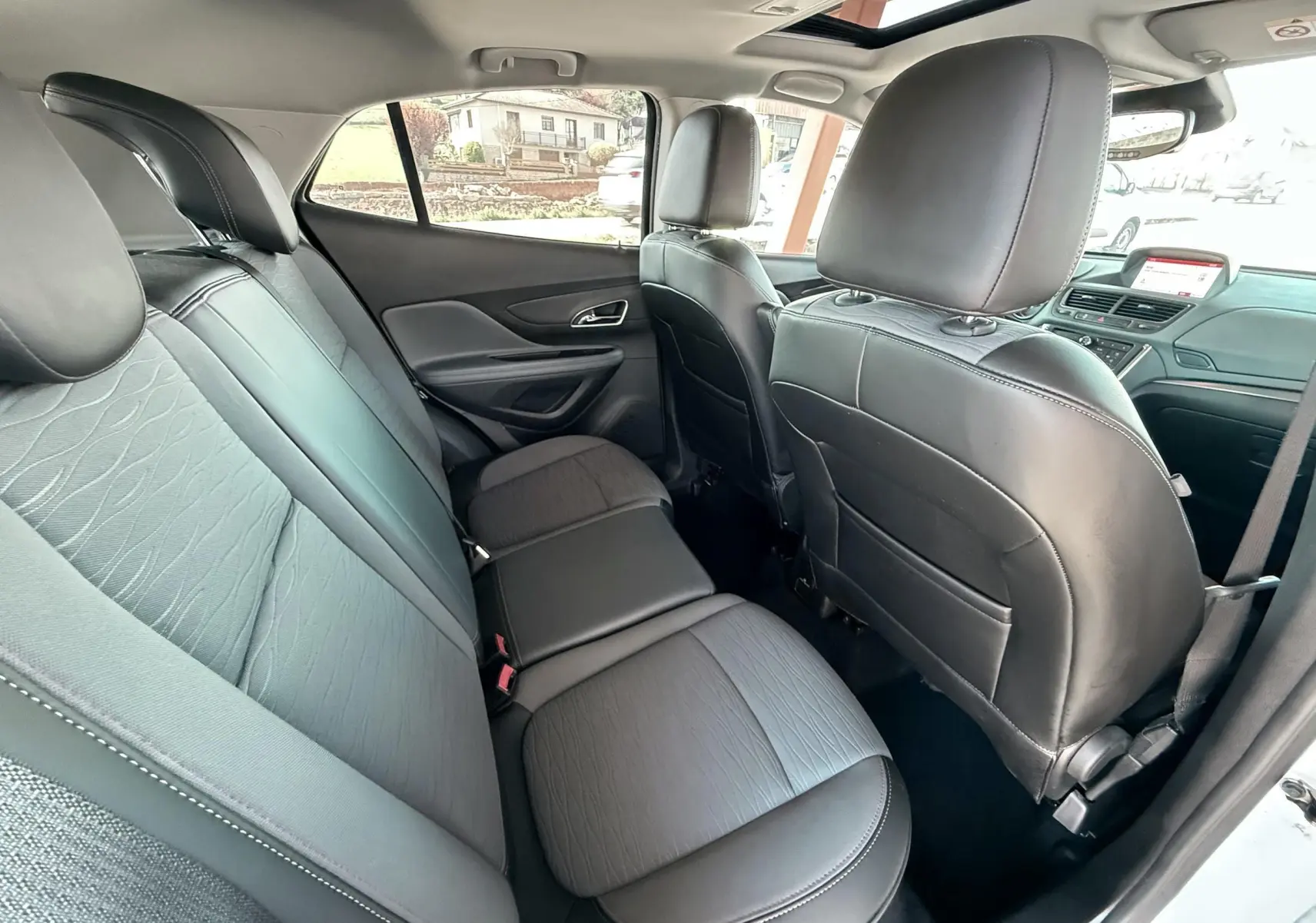 Vue intérieure arrière montrant les sièges arrière en cuir noir et tissu gris du Opel Mokka X blanc.