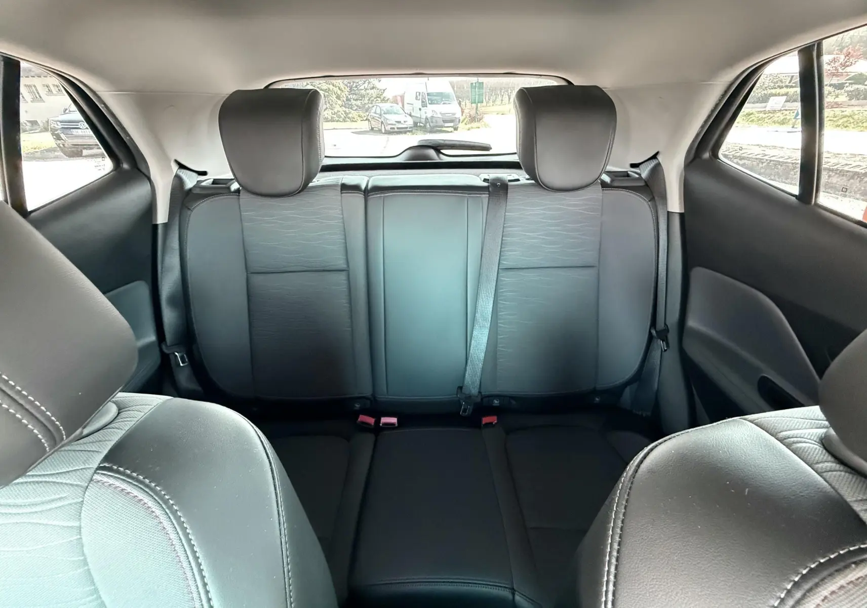 Vue intérieure arrière de l'Opel Mokka X 2016, sièges arrière en tissu noir avec appuie-têtes et ceinture de sécurité.