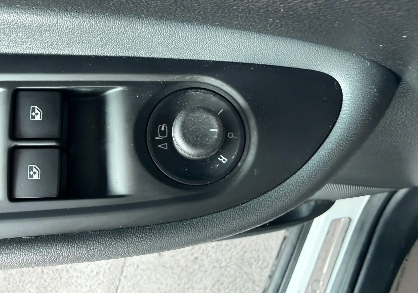 Gros plan sur les commandes de réglage des rétroviseurs et des vitres côté conducteur de l'Opel Mokka X blanc.