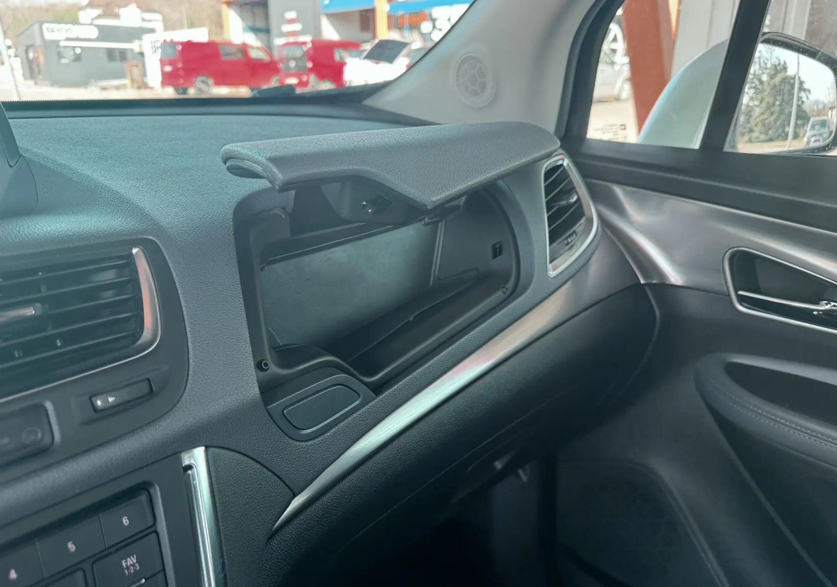 Intérieur de l'Opel Mokka X 2016, vue côté passager sur la boîte à gants ouverte et garnitures grises et noires.