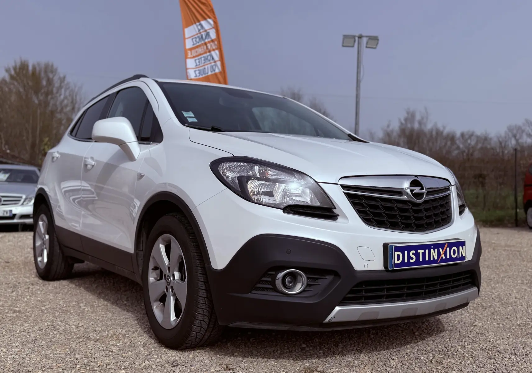 Opel Mokka X blanc vue 3/4 avant droit, avec calandre noire et pare-chocs noir contrastant.