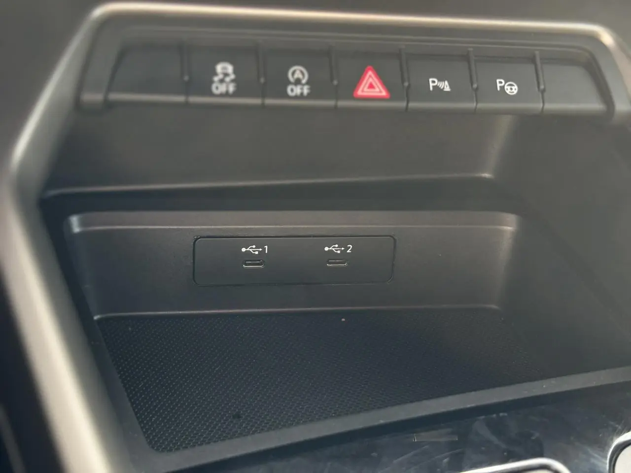 Gros plan sur la console centrale noire de l'Audi A3 Sportback 2023 avec ports USB-C et boutons de contrôle au-dessus.