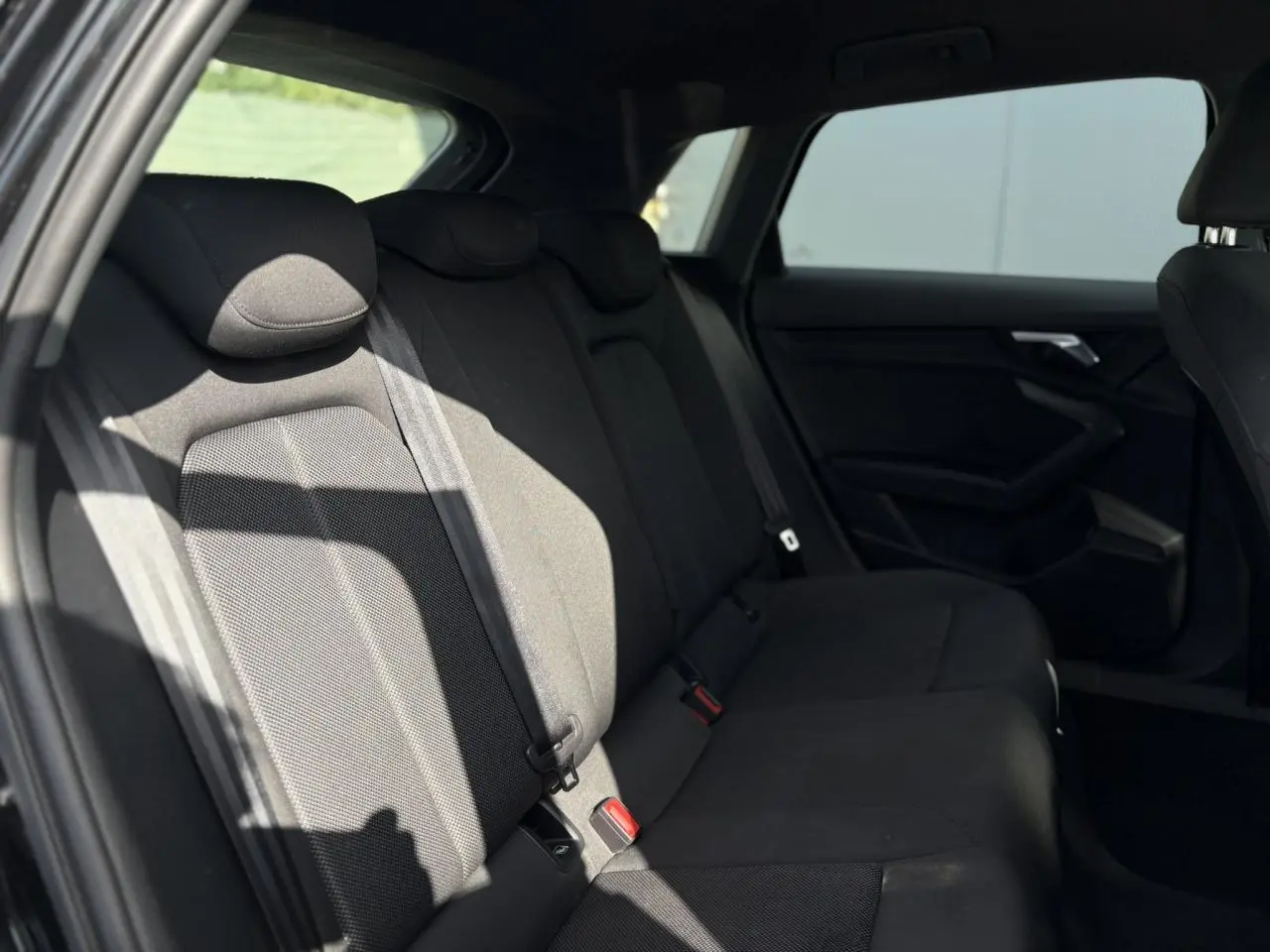 Vue intérieure arrière de l'Audi A3 Sportback 2023 en Noir Mythe, montrant les sièges arrière en tissu sombre.