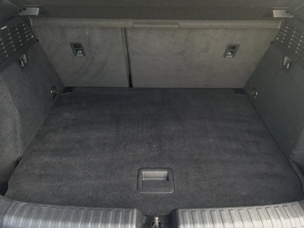 Coffre spacieux vu de face, revêtement noir, avec fixations Isofix et tapis de sol dans un Audi A3 Sportback 2023.