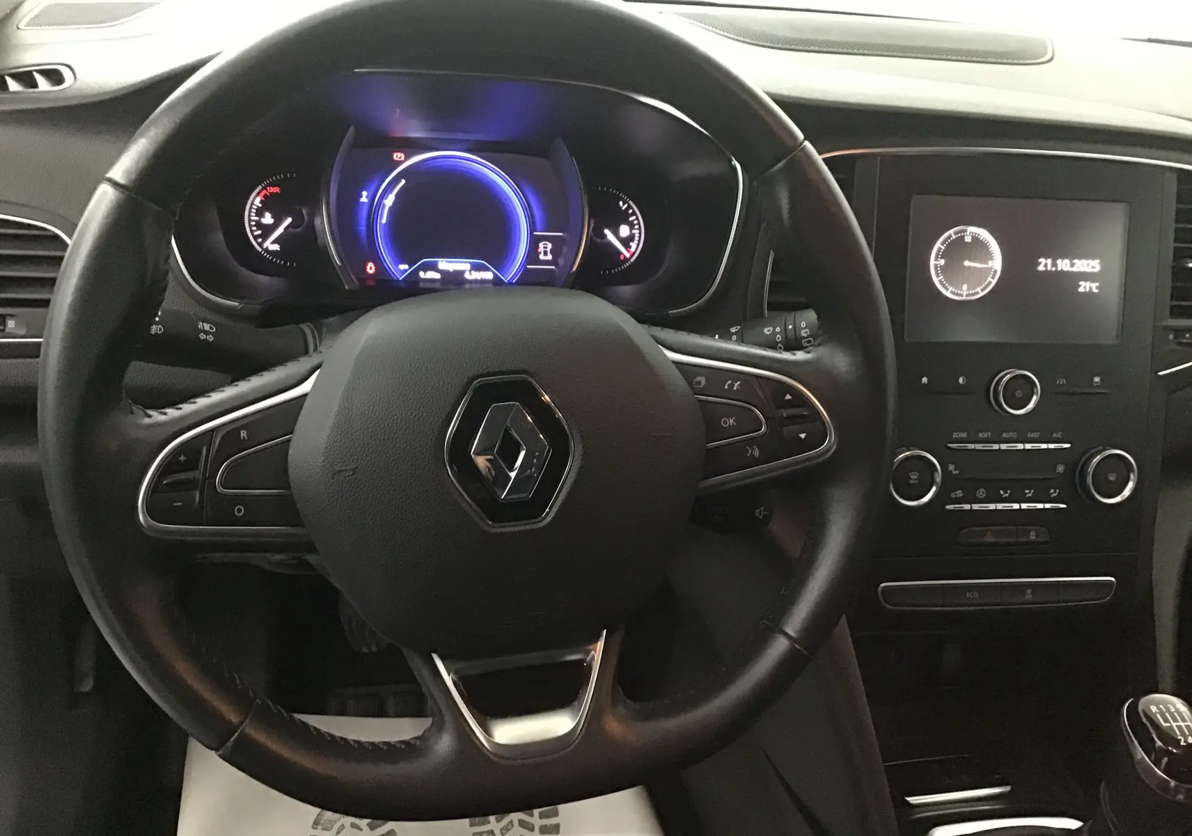 Vue rapprochée du volant Renault avec tableau de bord numérique bleu et console centrale noire de la Mégane IV Berline 2019.