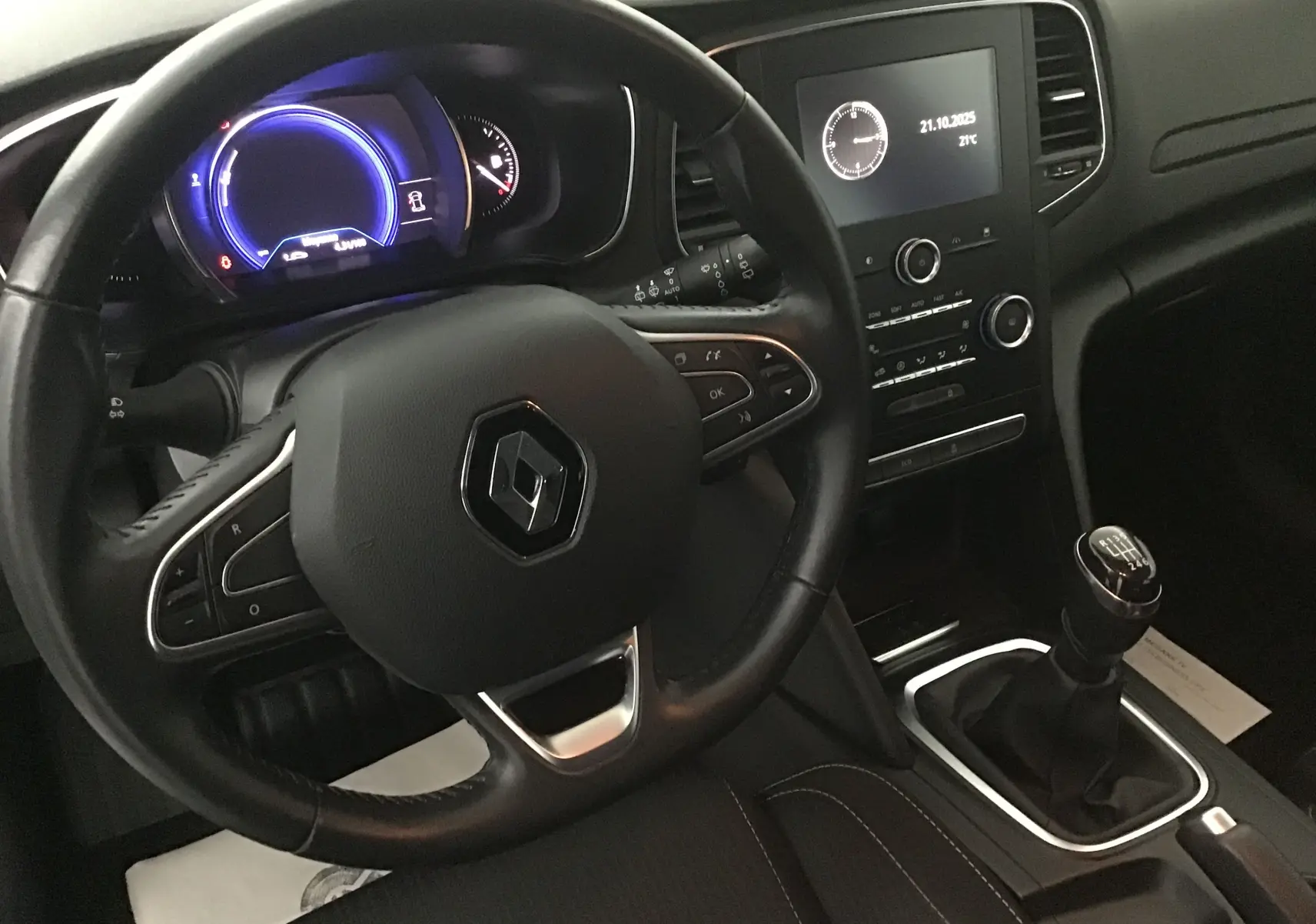 Vue intérieure côté conducteur de la Renault Mégane IV Business 2019, volant cuir noir et levier de vitesse manuel visibles.