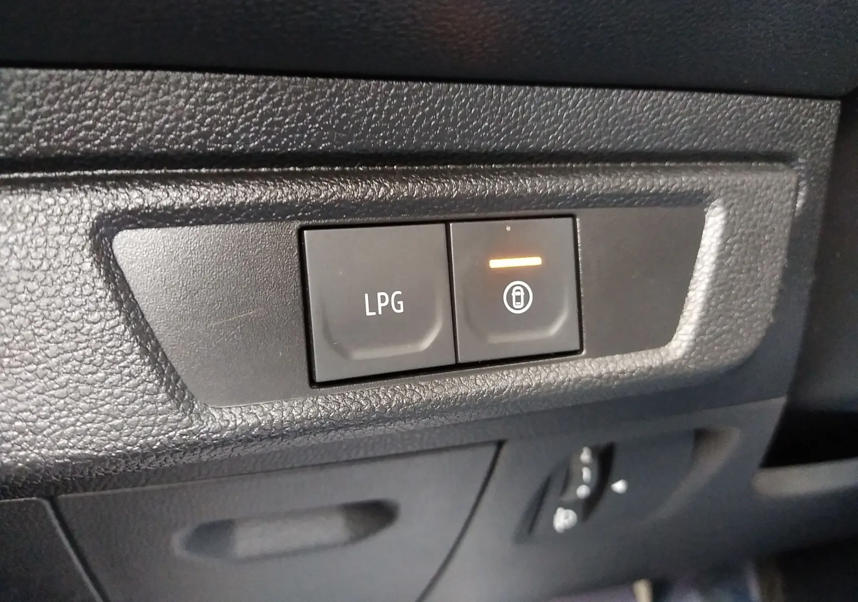 Gros plan sur les boutons de commande LPG et verrouillage dans l’habitacle noir de la Dacia Sandero 2024 gris.