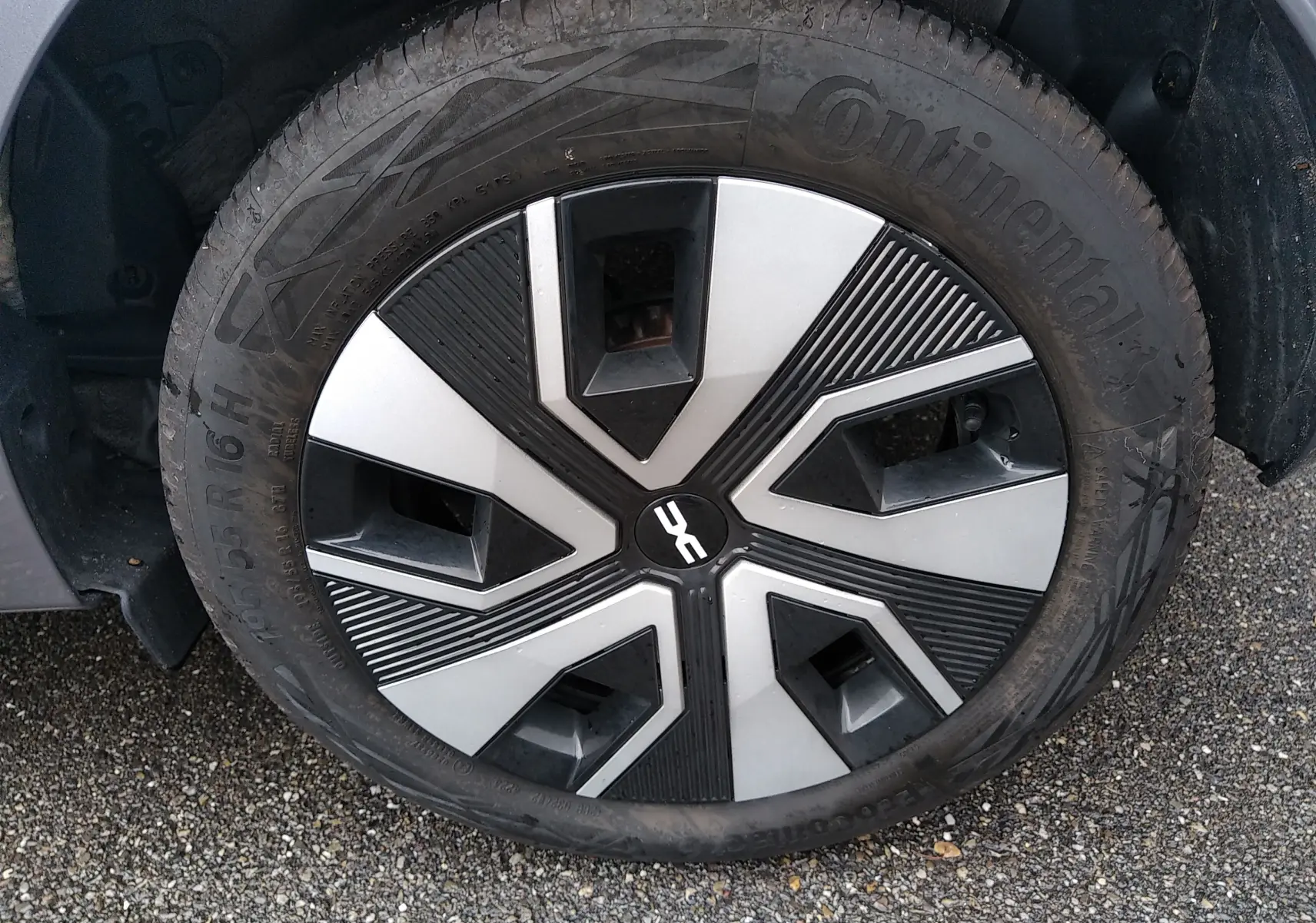 Gros plan sur la roue avant gauche de la Dacia Sandero gris 2024, mettant en valeur la jante au design géométrique noir et argent.