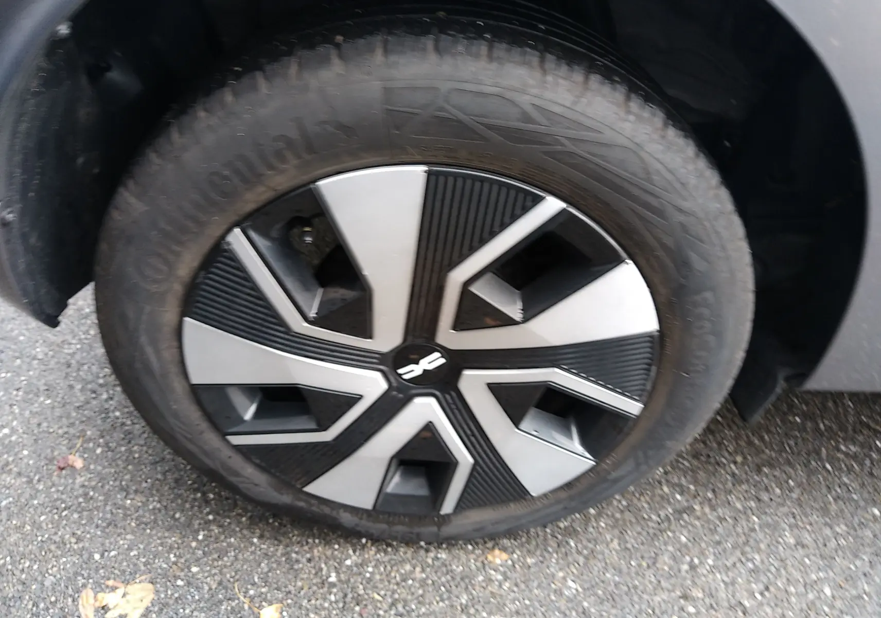 Gros plan sur la roue avant droite d'une Dacia Sandero gris 2024 avec jante au design noir et argenté.