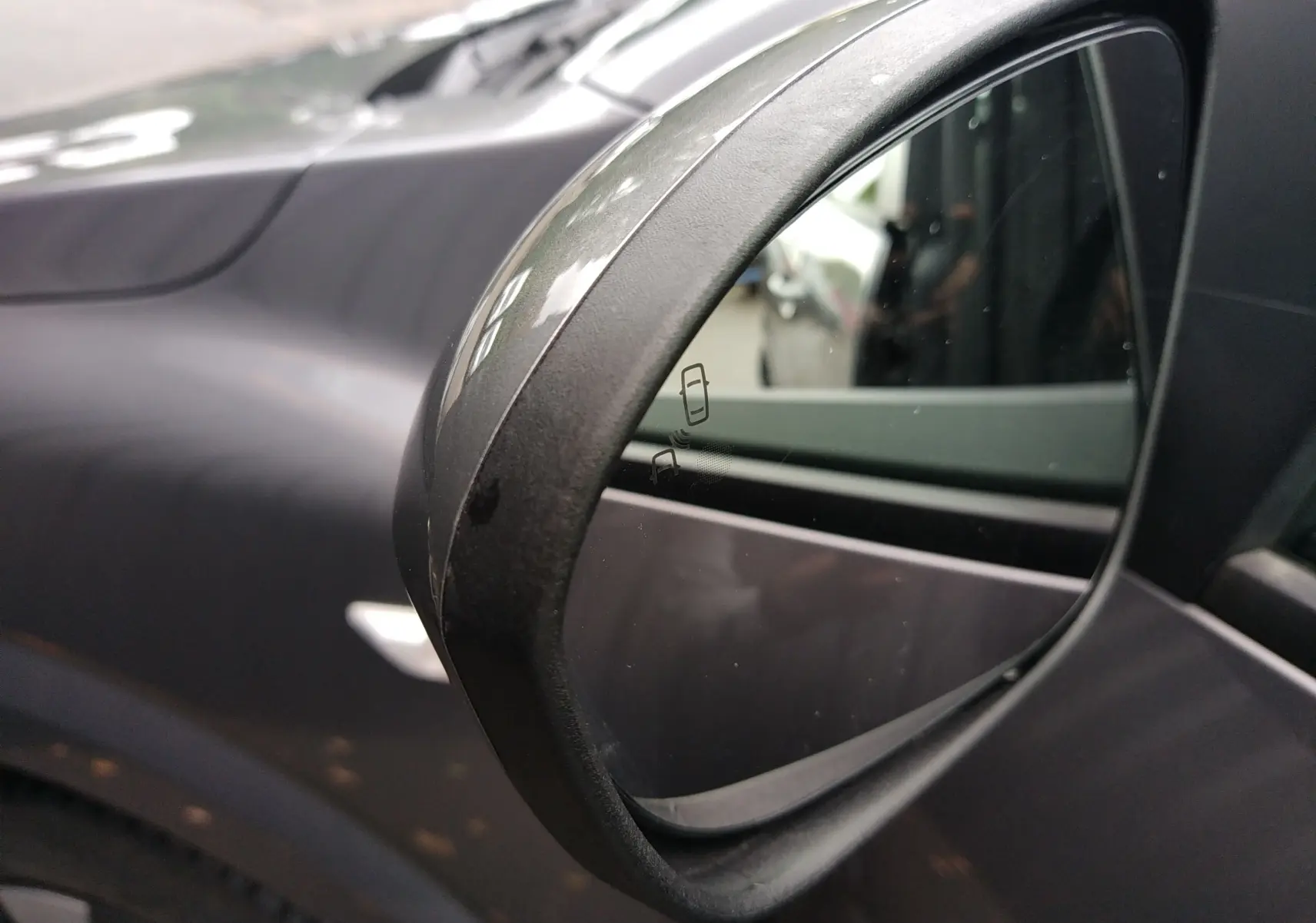 Gros plan sur le rétroviseur côté droit gris d'une Dacia Sandero 2024 avec indicateur d'angle mort visible.