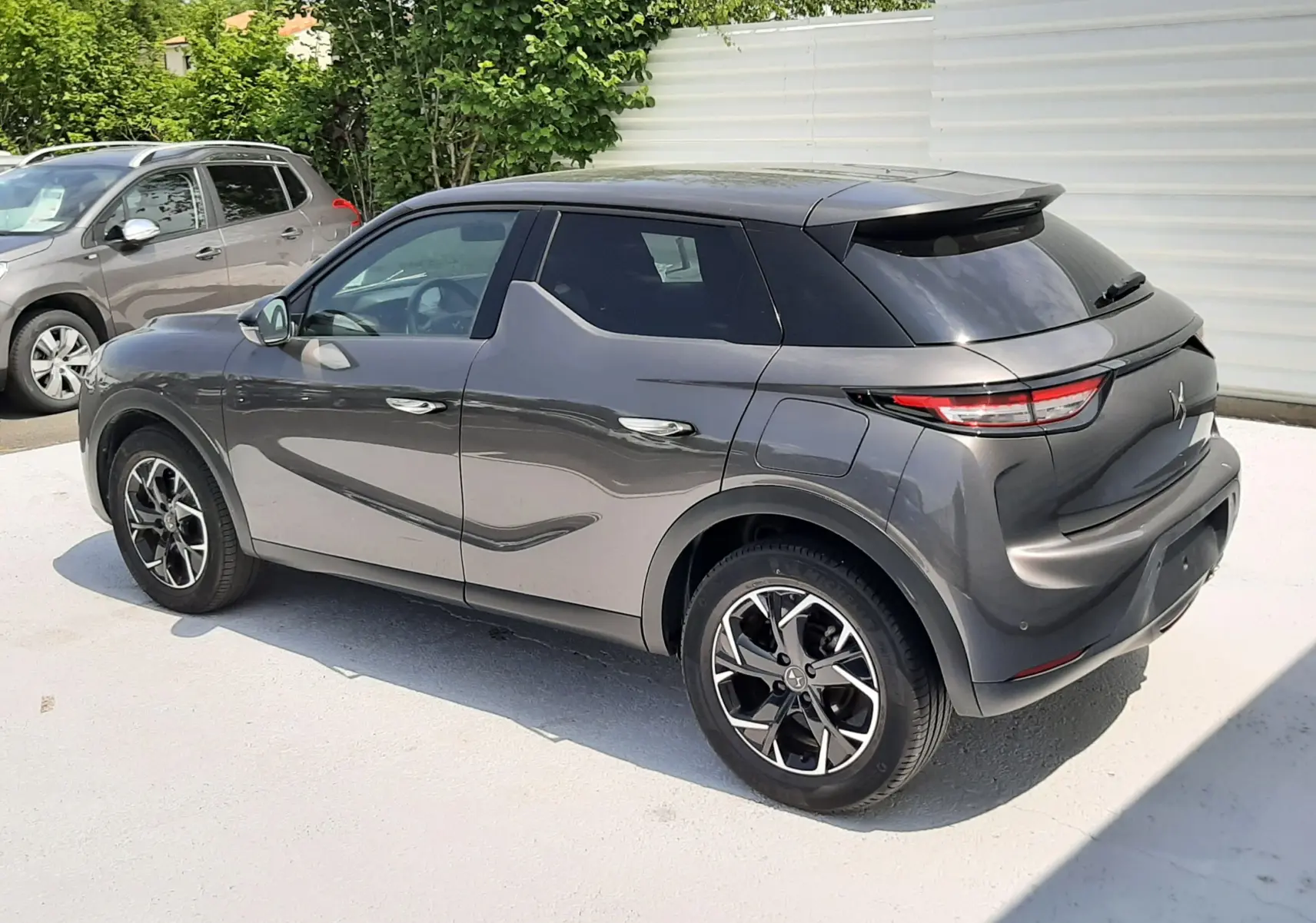 Vue 3/4 arrière droite d'un DS3 Crossback gris platinium métallisé avec toit noir et jantes bicolores.