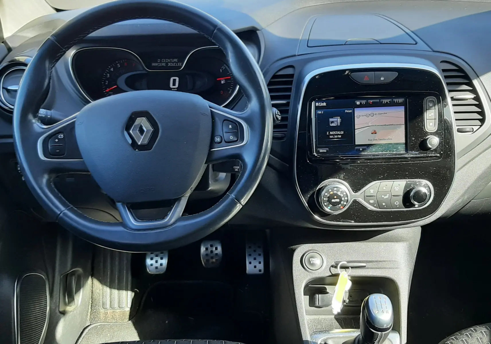 Vue intérieure frontale du tableau de bord et volant noir d'un Renault Captur 2018 avec boîte manuelle et écran tactile central.