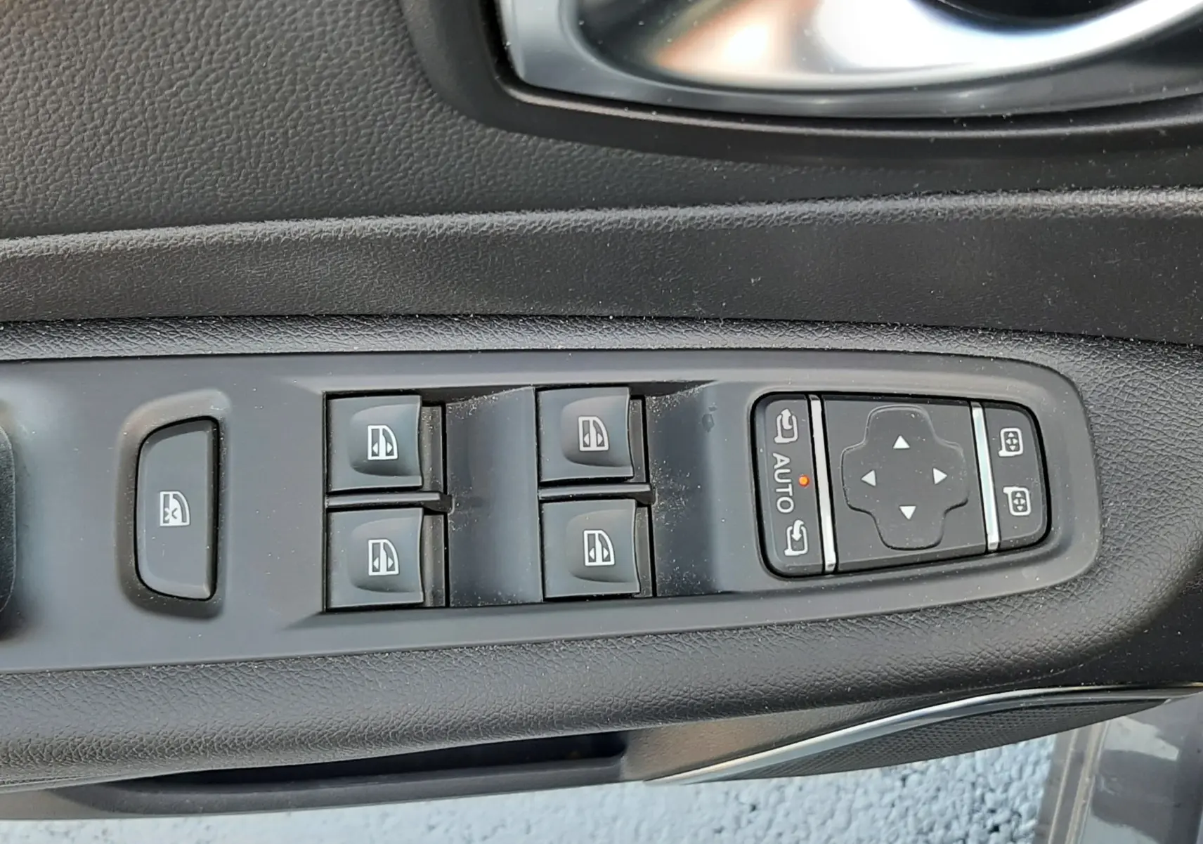 Gros plan sur la commande des vitres et rétroviseurs côté conducteur du Renault Captur gris cassiope avec intérieur noir.