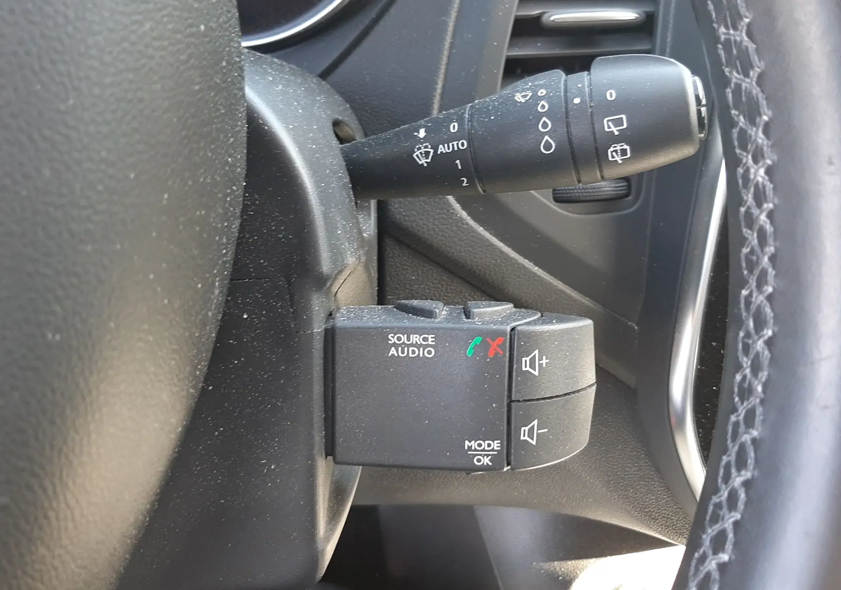 Gros plan sur la commande audio au volant et le commodo d'essuie-glace du Renault Captur gris cassiope 2018, intérieur noir.