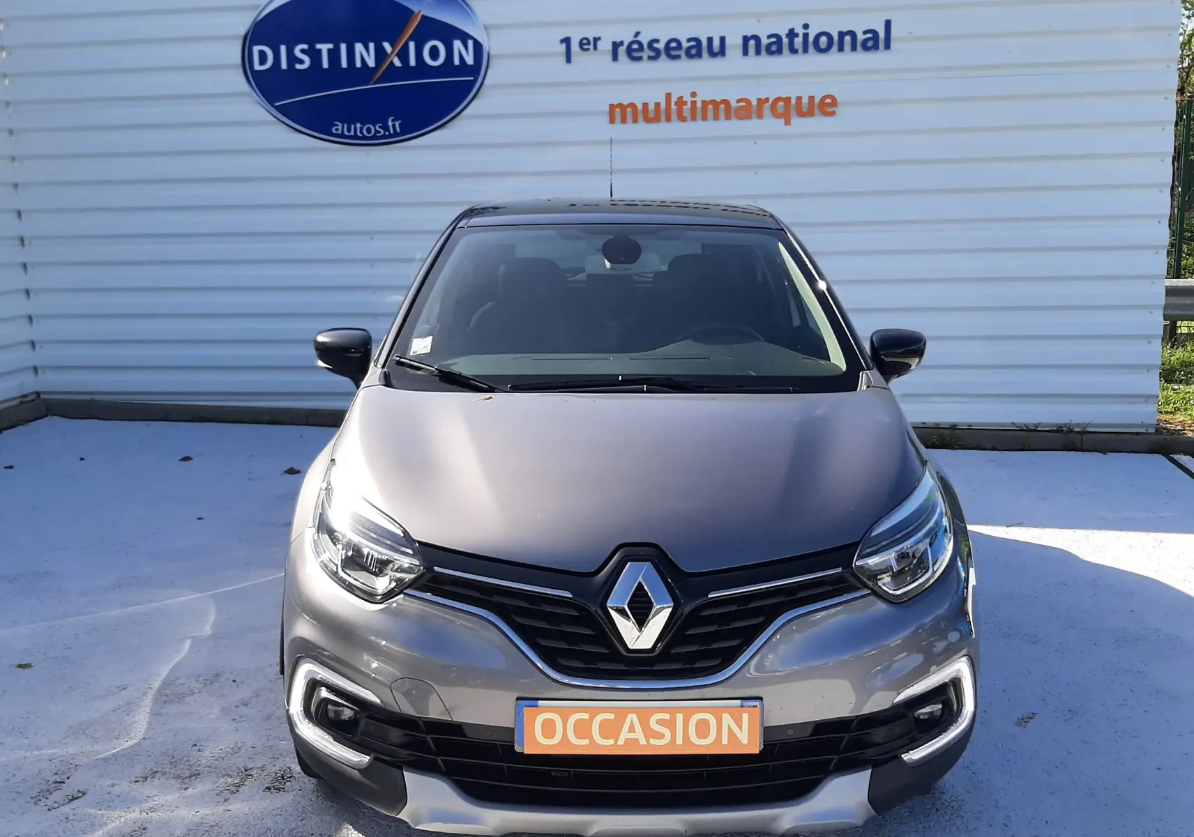 Vue frontale d'un Renault Captur gris Cassiope avec toit noir, badge Renault visible et plaque "OCCASION" orange.