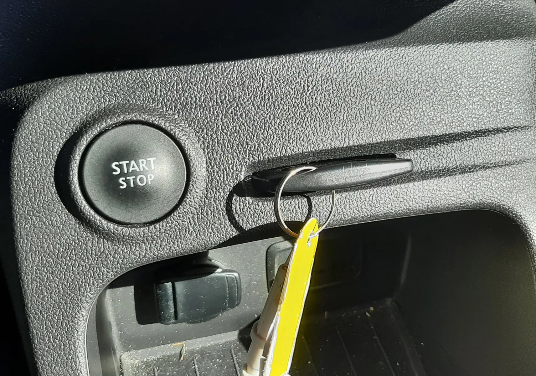 Gros plan sur le bouton Start/Stop et la clé insérée dans la poignée de la console intérieure noire du Renault Captur gris cassiope.