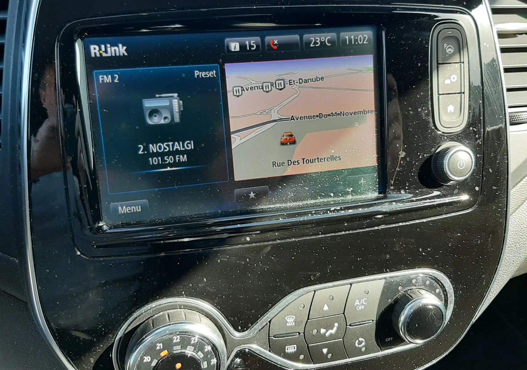 Vue rapprochée de l'écran tactile R-Link et de la console centrale noire du Renault Captur gris cassiope avec toit noir.