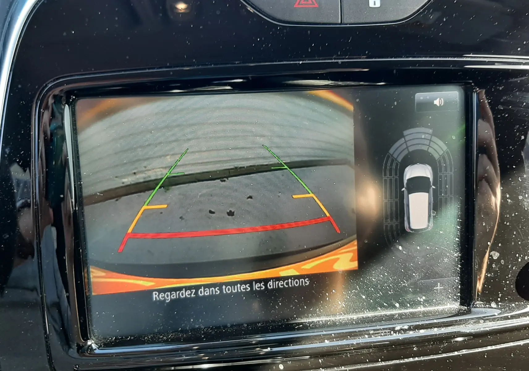 Écran de caméra de recul du Renault Captur gris cassiope avec lignes de guidage colorées et alertes de proximité.