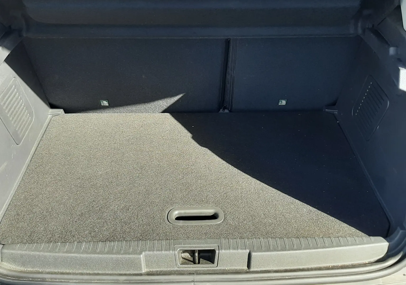 Coffre ouvert vu de l'arrière du Renault Captur gris cassiope avec intérieur noir, montrant un espace de chargement propre.