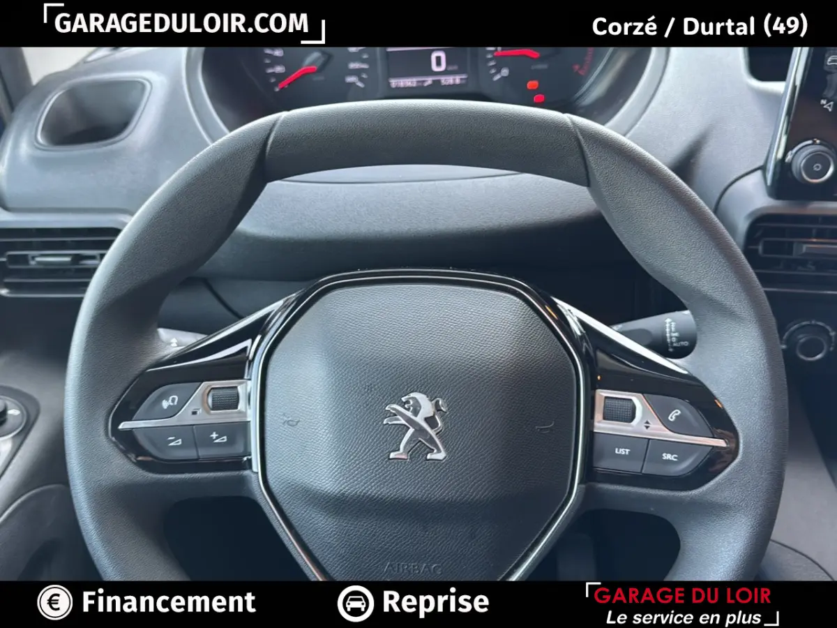 Vue rapprochée du volant noir du Peugeot Rifter 2024 avec commandes intégrées et tableau de bord digital en arrière-plan.