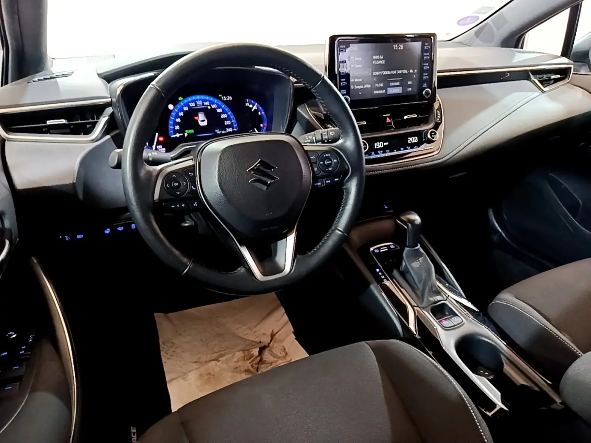 Vue intérieure du poste de conduite de la Suzuki Swace 1.8 Hybrid Privilege avec volant cuir multifonctions et écran tactile central.