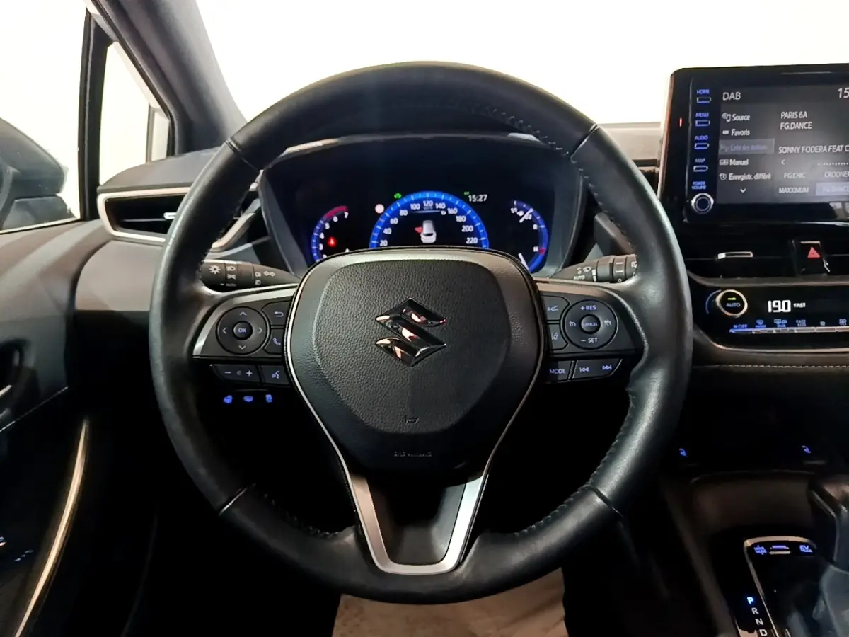 Vue rapprochée du volant cuir et alu multifonctions de la Suzuki Swace 1.8 Hybrid Privilege avec tableau de bord digital.