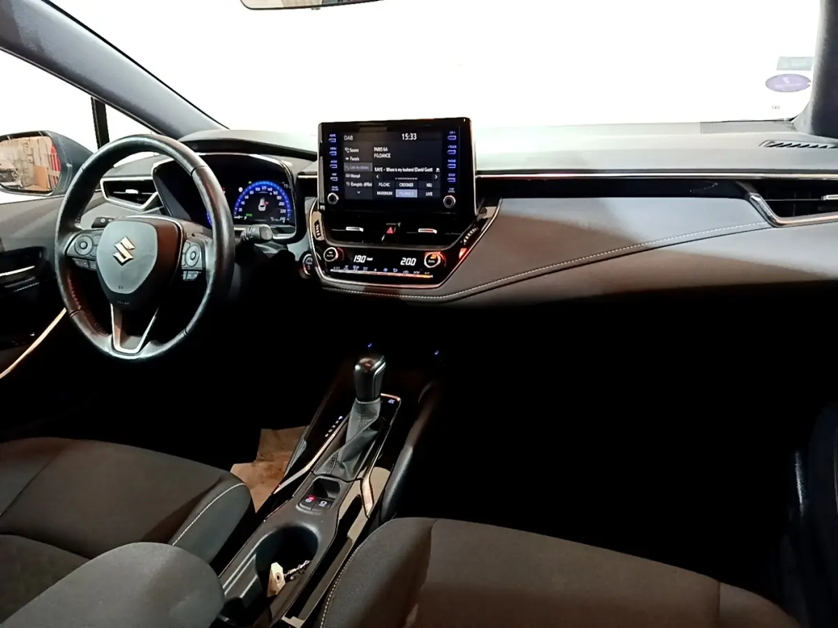 Vue intérieure avant du Suzuki Swace 1.8 Hybrid Privilege 2021, tableau de bord noir avec écran tactile central et volant cuir.