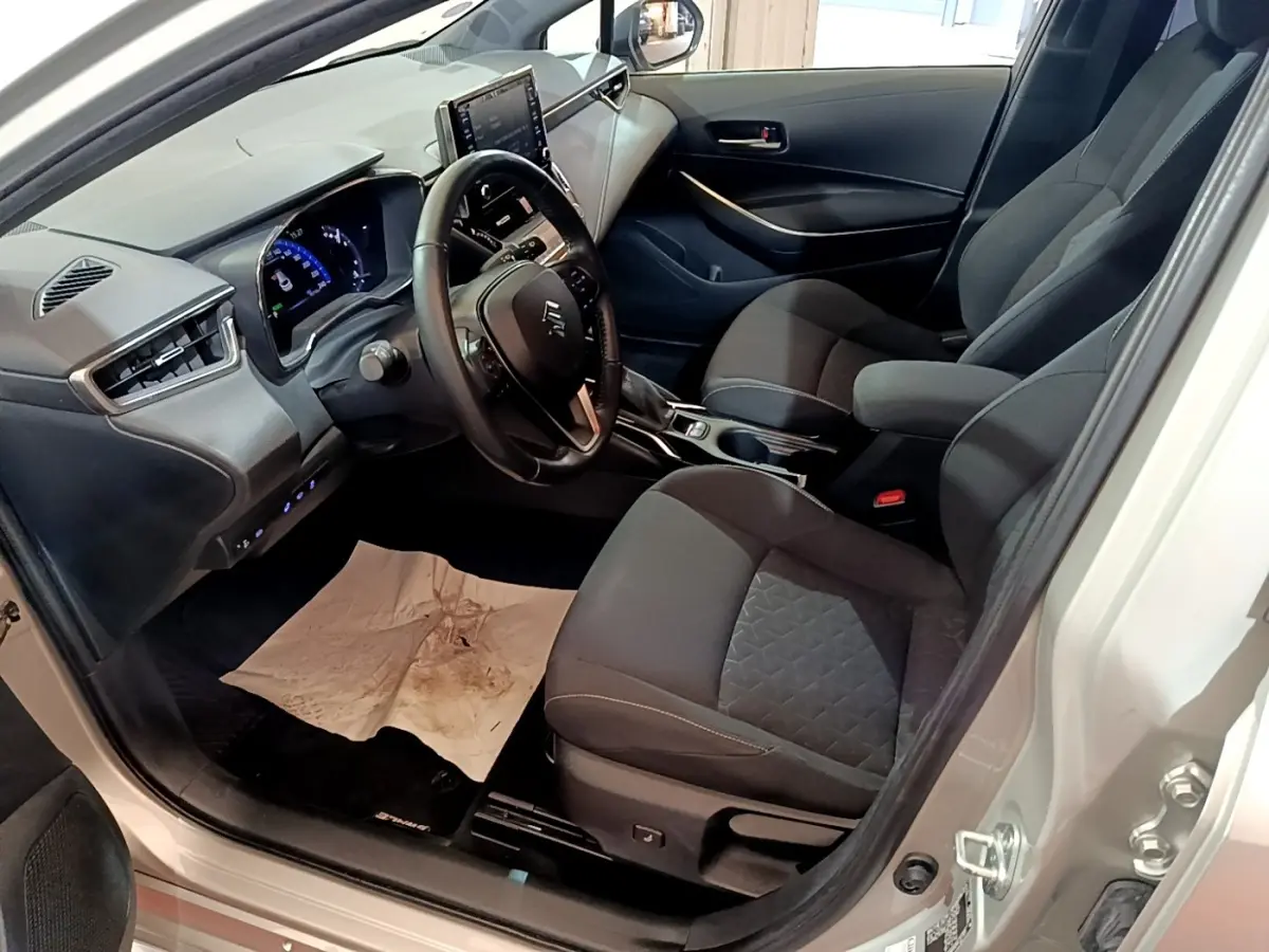 Vue intérieure côté conducteur de la Suzuki Swace gris clair, volant cuir multifonctions et tableau de bord digital.