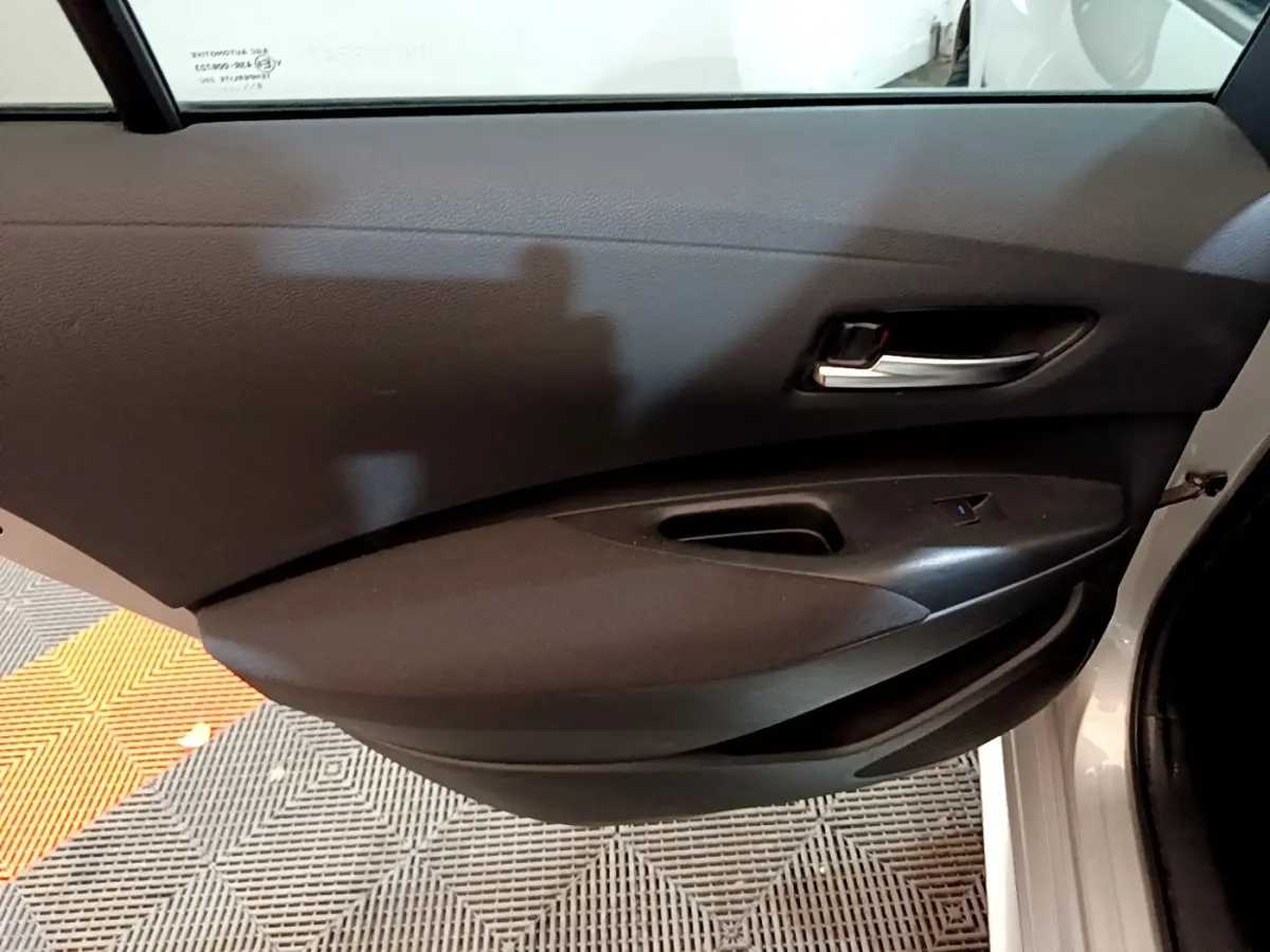 Vue rapprochée de la porte arrière droite gris clair de la Suzuki Swace 1.8 Hybrid Privilege avec poignée intérieure noire.