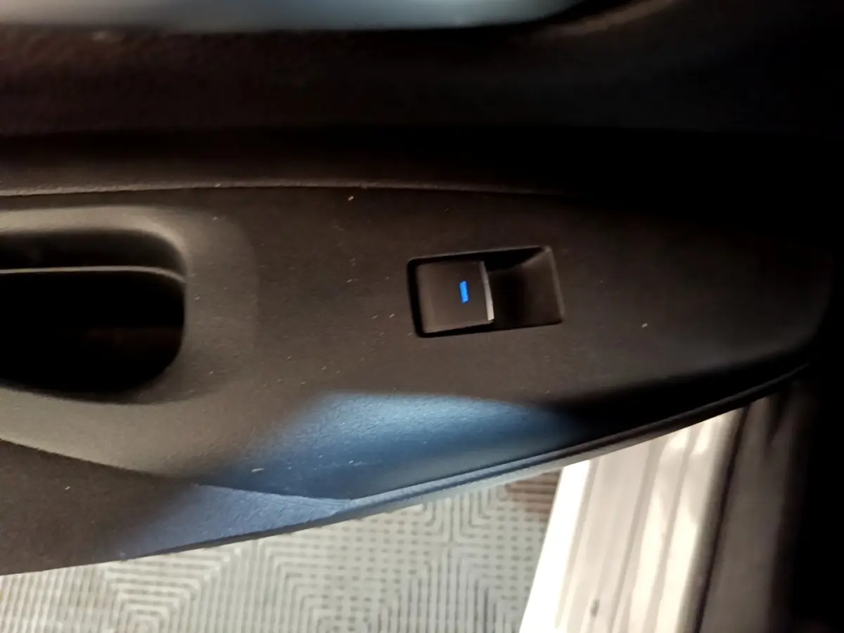 Bouton de commande de lève-vitre noir sur panneau de porte intérieur, détail de la Suzuki Swace gris clair.