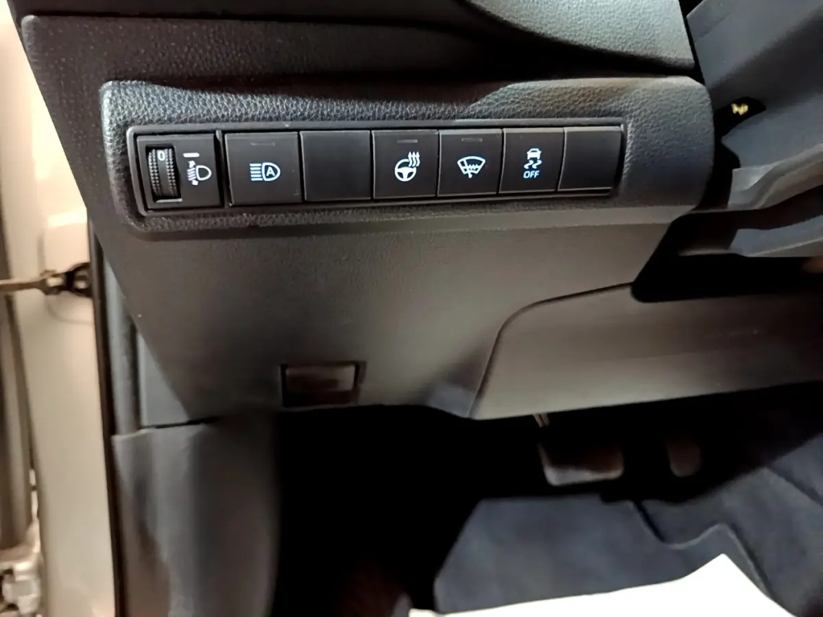 Vue intérieure du tableau de bord côté gauche du Suzuki Swace gris clair, avec commandes d'éclairage et assistance au freinage.