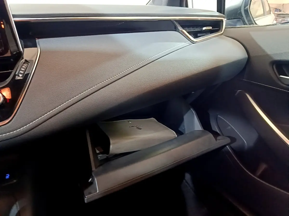 Intérieur de la Suzuki Swace 1.8 Hybrid Privilège 2021, vue côté passager sur la boîte à gants ouverte et tableau de bord gris.