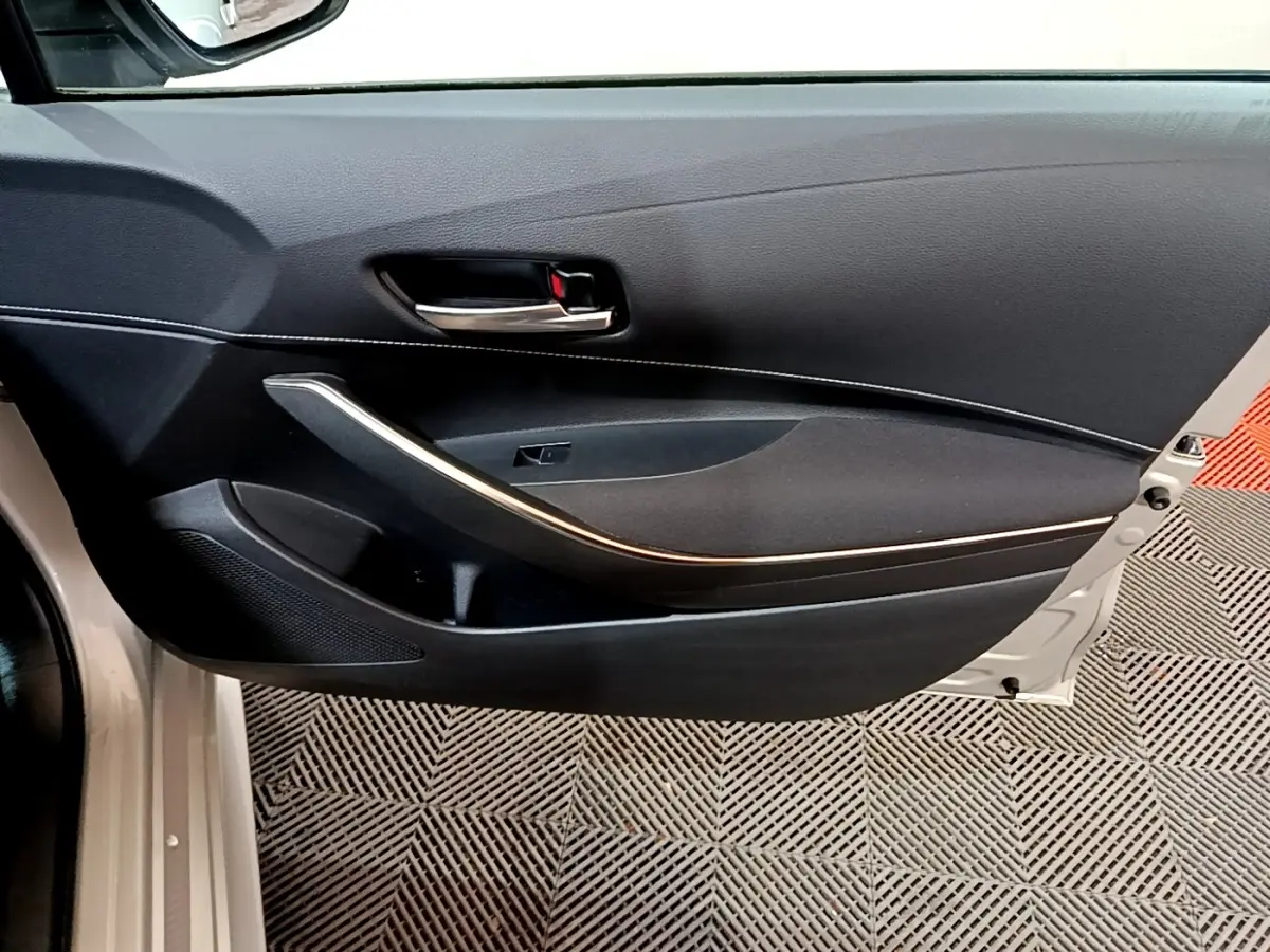 Vue intérieure de la porte avant gauche noire avec poignée chrome et insert gris clair du Suzuki Swace 1.8 Hybrid Privilege.