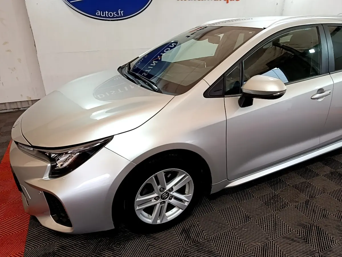 Vue 3/4 avant droit d'une Suzuki Swace gris clair avec jantes alliage et rétroviseur assorti.