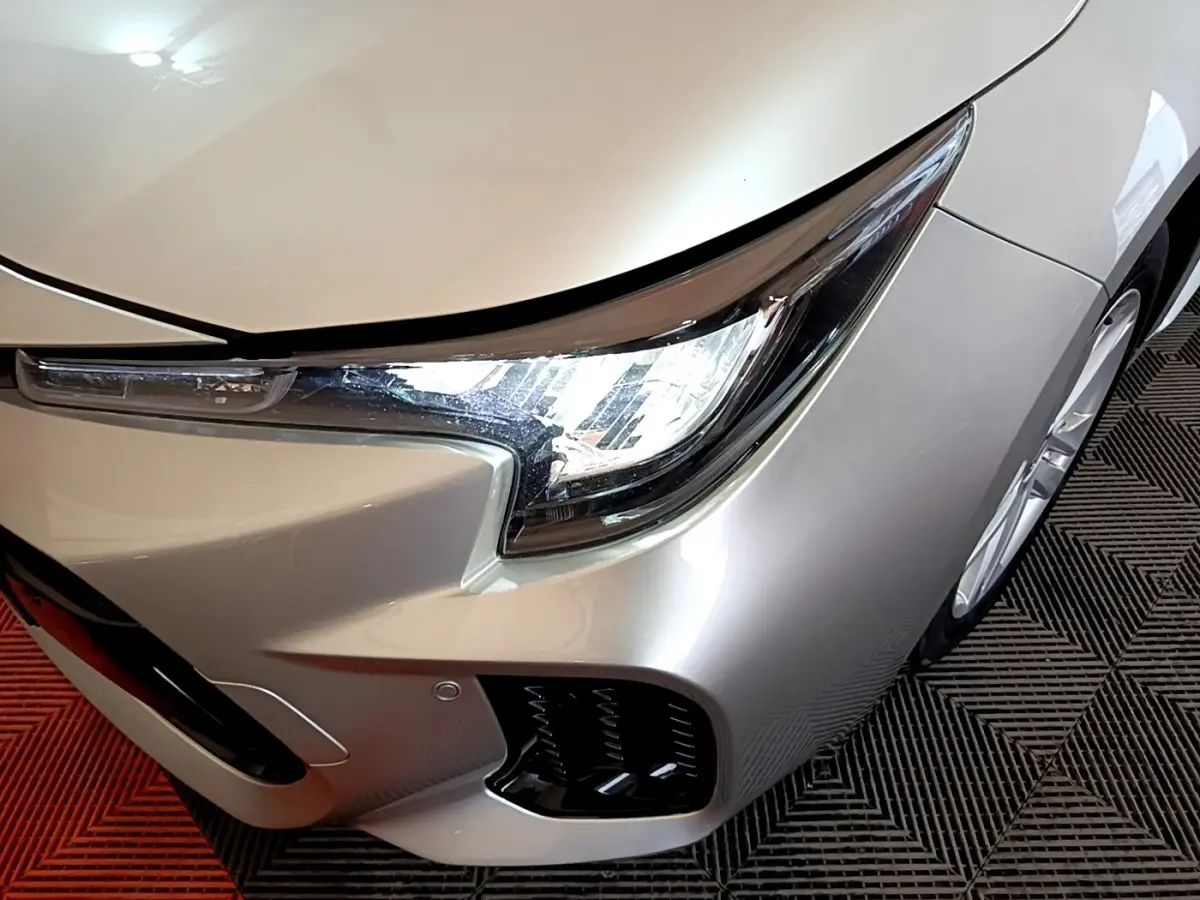 Vue 3/4 avant droit d'une Suzuki Swace gris clair mettant en valeur son phare LED et la calandre inférieure.