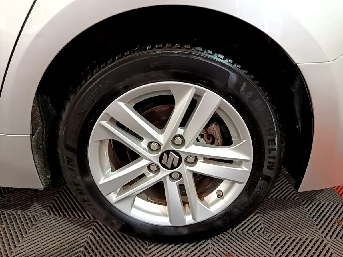 Gros plan sur la roue avant gauche gris clair d'une Suzuki Swace 1.8 Hybrid Privilege avec jante alliage.