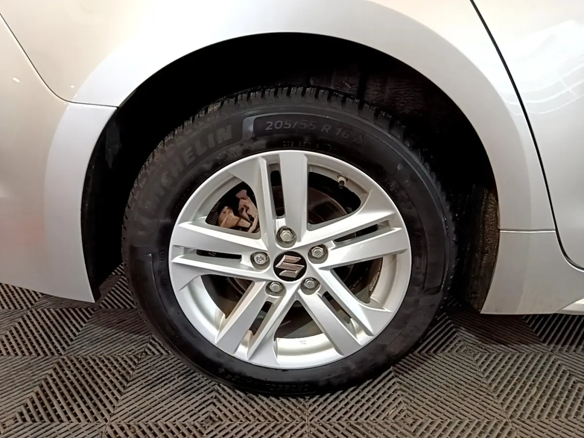 Gros plan sur la roue arrière droite d'une Suzuki Swace gris clair, montrant l'aile et une partie de la carrosserie.