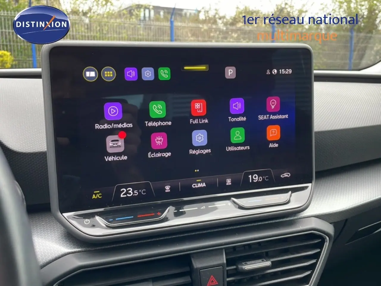 Vue rapprochée de l'écran tactile central du tableau de bord du SEAT LEON ST bleu Fjord, affichant les réglages multimédias et climatiques.