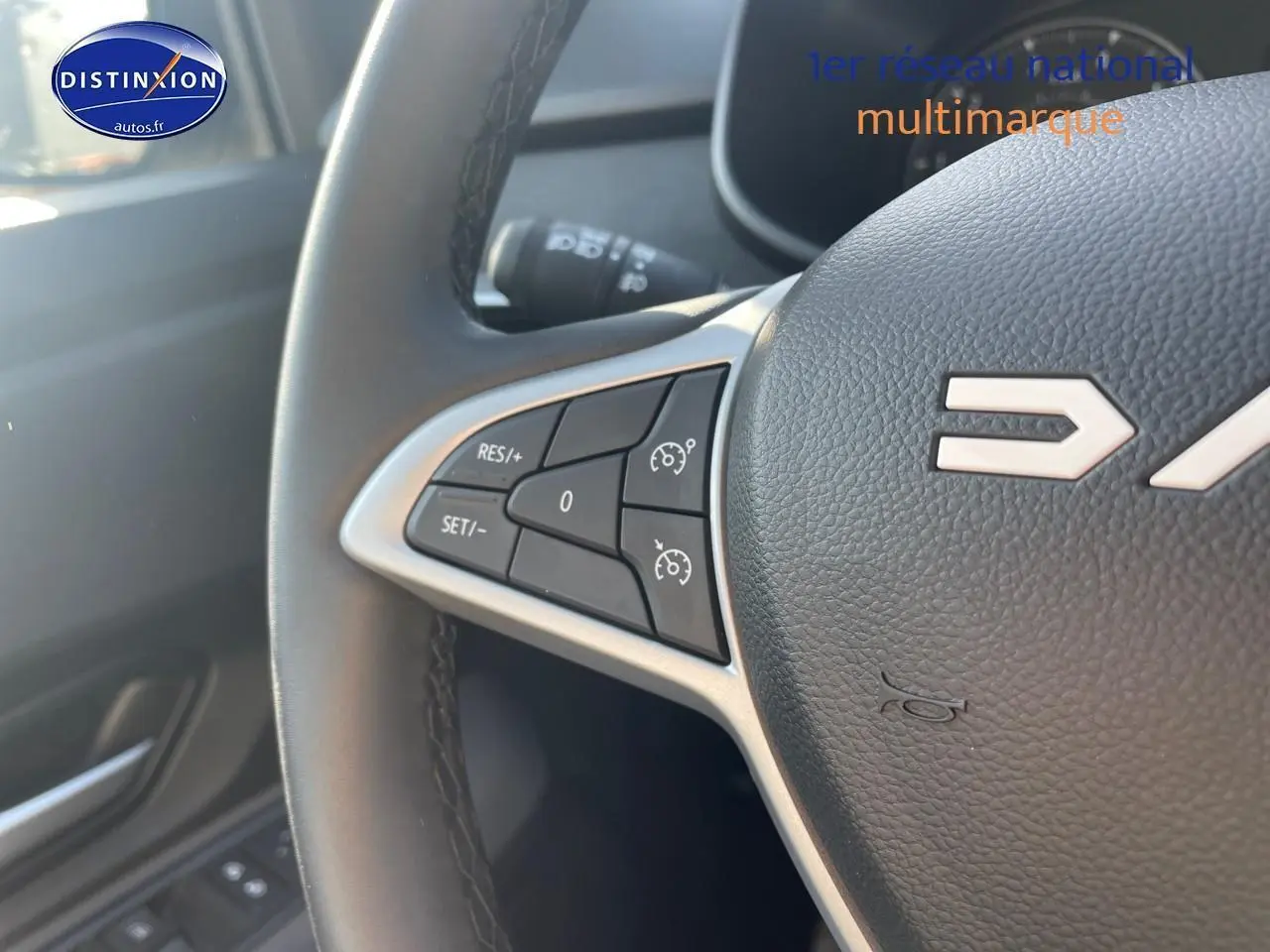 Gros plan sur le volant en cuir noir de la Dacia Sandero 2025 avec commandes de régulateur de vitesse intégrées.