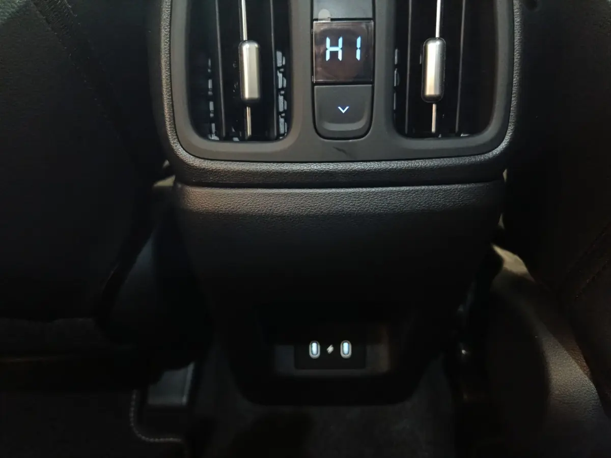 Vue rapprochée de la console arrière noire du Hyundai Tucson 2025 gris clair, avec commandes de ventilation et ports USB.