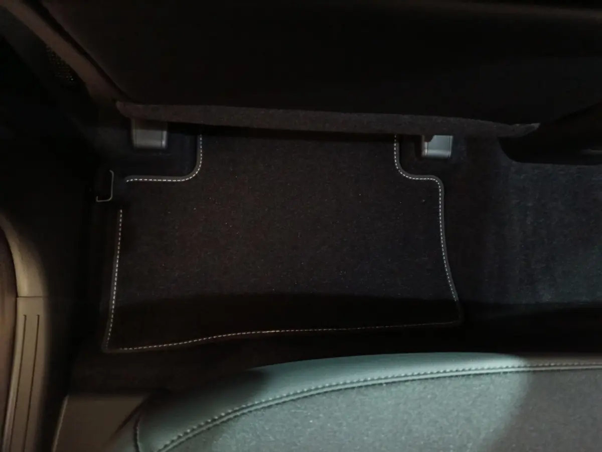 Tapis de sol noir avec surpiqûres blanches côté passager arrière du Hyundai Tucson gris clair 2025 hybride.