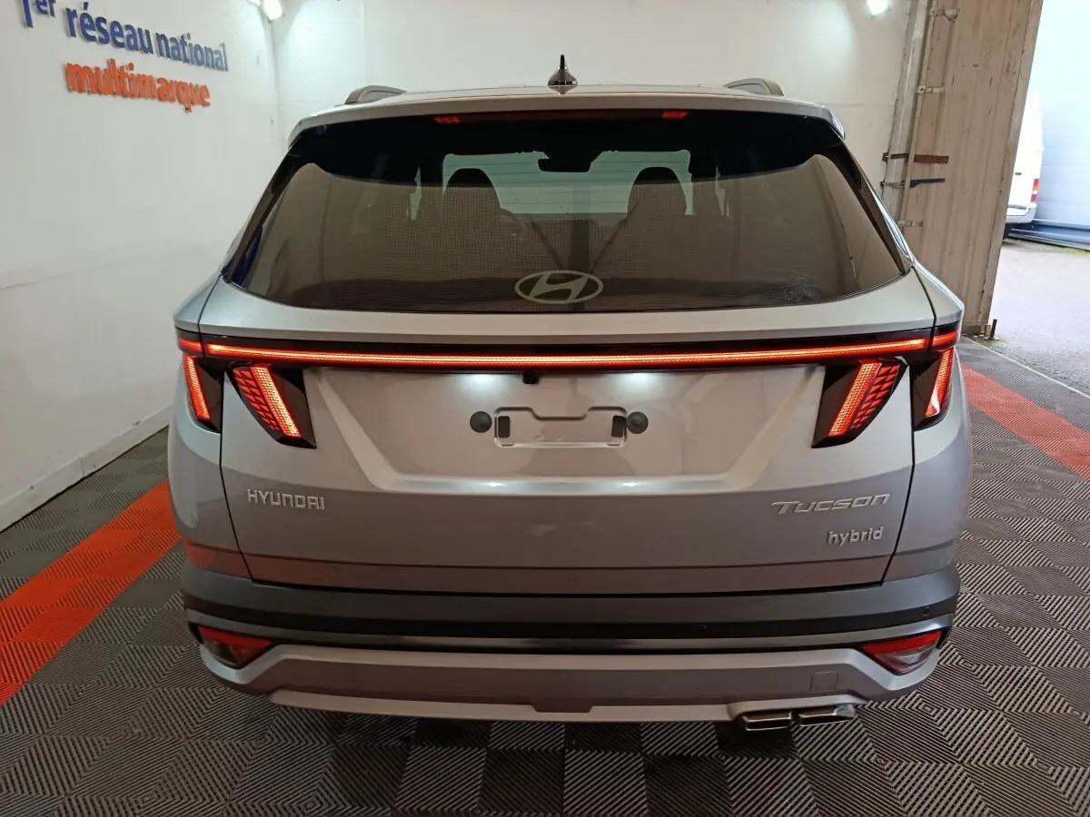 Vue arrière d’un Hyundai Tucson 1.6 Hybrid gris clair 2025 avec feux LED distinctifs et double sortie d’échappement.