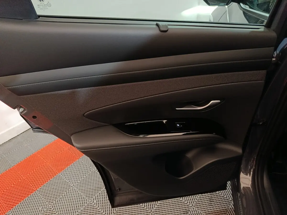 Intérieur côté gauche de la porte arrière d’un Hyundai Tucson gris clair, avec garniture tissu et cuir noir.