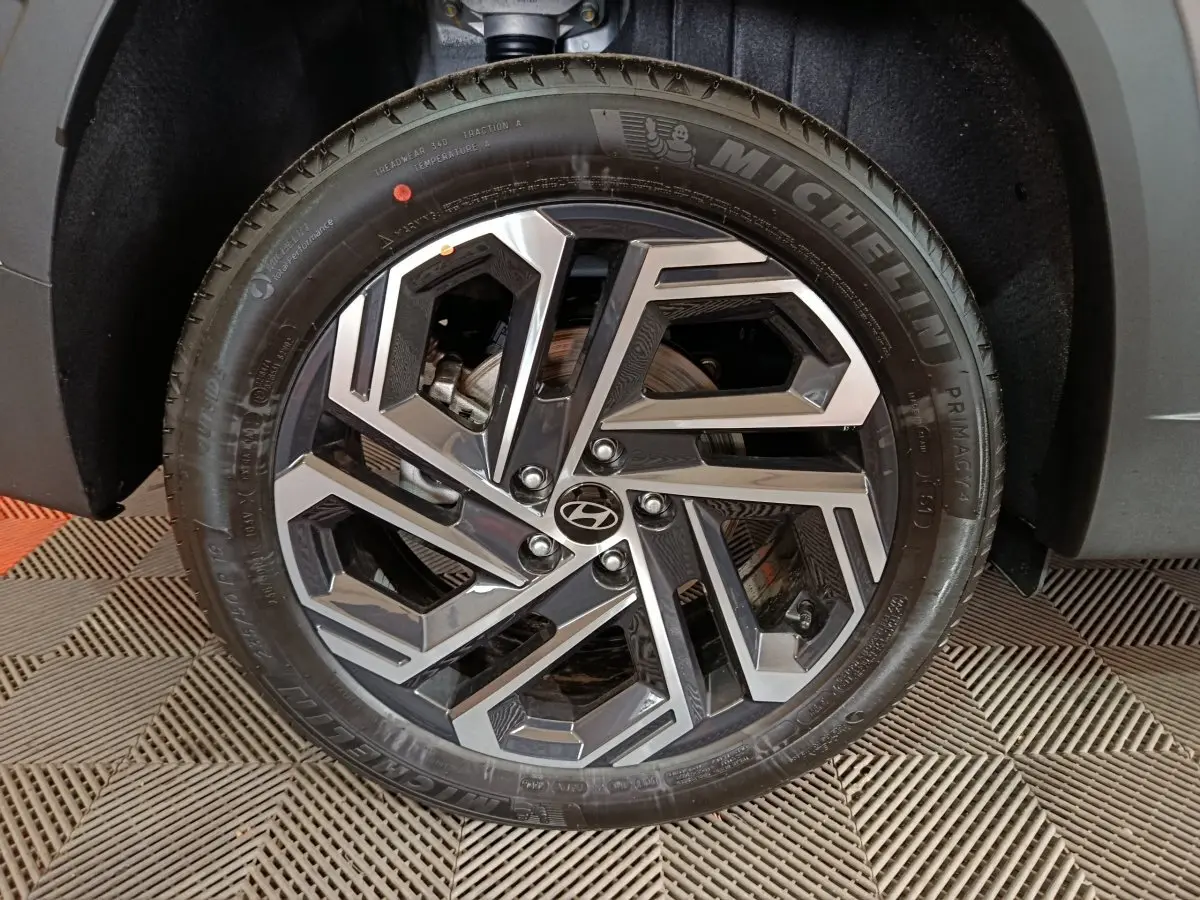 Gros plan sur la roue avant droite du Hyundai Tucson gris clair 2025 avec jante alliage au design géométrique.