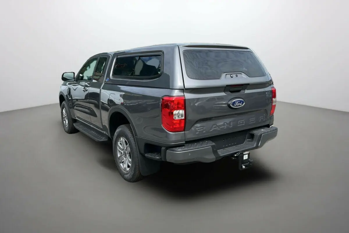 Ford Ranger gris carbone vu en 3/4 arrière droit avec hard-top vitré et attelage visible.