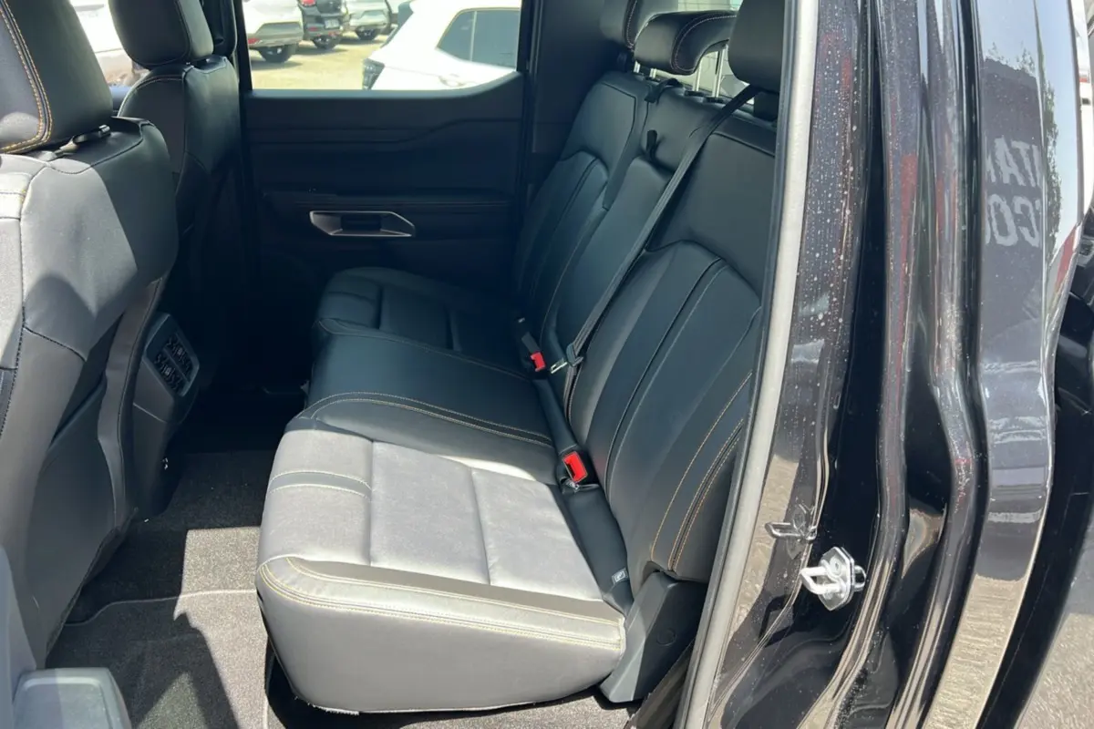 Vue intérieure côté arrière droit du Ford Ranger Wildtrak Plus 2026 noir agate, sièges arrière en cuir noir avec surpiqûres jaunes.